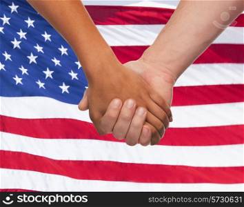 friendship, patriotism, gesture and people concept - closeup of two hands hands holding over american flag