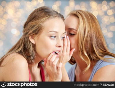 friendship, people and communication concept - happy young women gossiping and whispering to ear over lights background. happy young women whispering gossip
