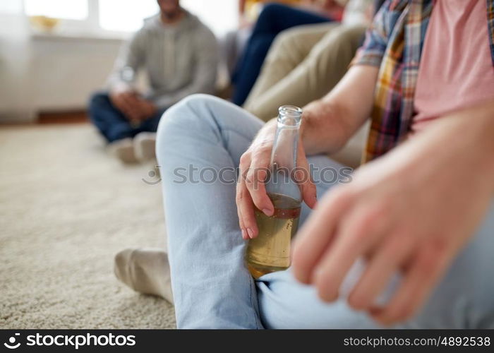 friendship, people and entertainment concept - close up of man with beer bottle and friends at home