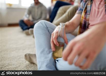 friendship, people and entertainment concept - close up of man with beer bottle and friends at home