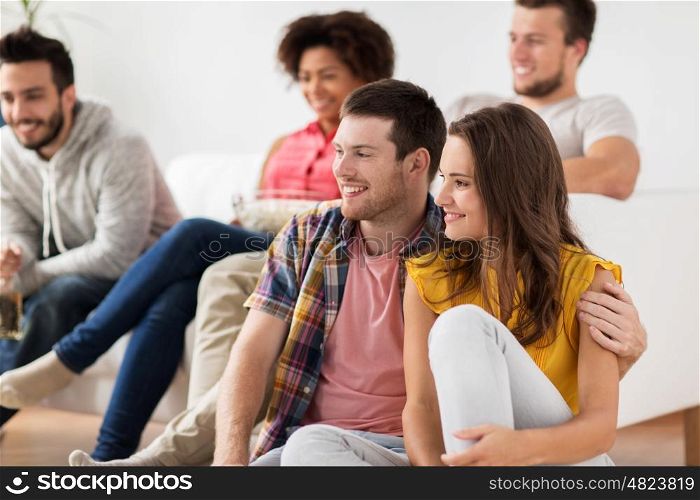 friendship, people and entertainment concept - happy couple with friends watching tv at home