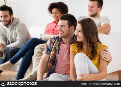 friendship, people and entertainment concept - happy couple with friends watching tv at home