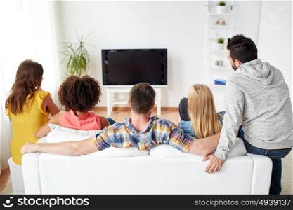 friendship, people and entertainment concept - happy friends watching tv at home. happy friends watching tv at home