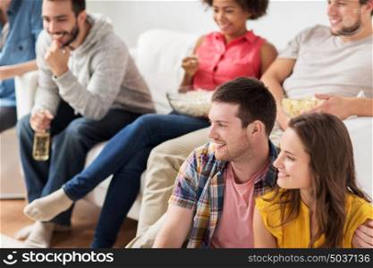 friendship, people and entertainment concept - happy friends with popcorn and beer watching tv at home. happy friends watching tv at home