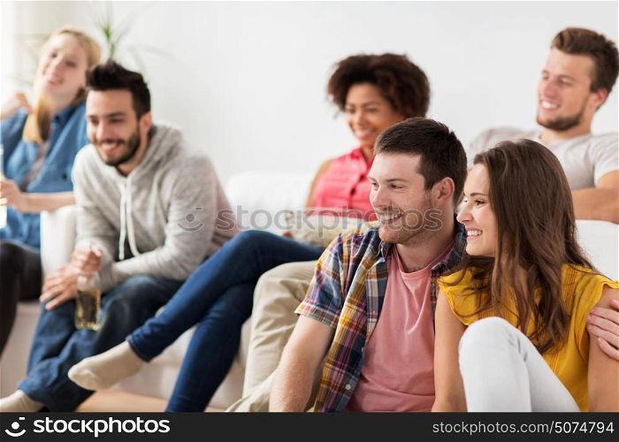 friendship, people and entertainment concept - happy friends with popcorn and beer watching tv at home. happy friends watching tv at home