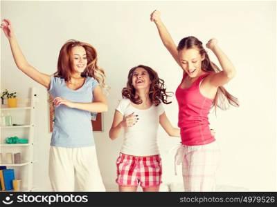 friendship, people and pajama party concept - happy friends or teenage girls having fun and jumping on bed at home. happy friends or teen girls having fun at home