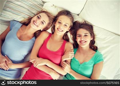 friendship, people and pajama party concept - happy friends or teenage girls having fun and lying in bed at home. happy young women in bed at home pajama party