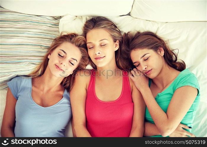 friendship, people and pajama party concept - happy friends or teenage girls sleeping in bed at home. happy young women sleeping in bed at home