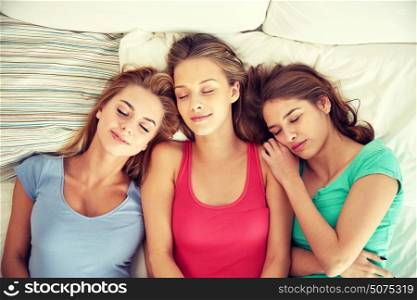 friendship, people and pajama party concept - happy friends or teenage girls sleeping in bed at home. happy young women sleeping in bed at home