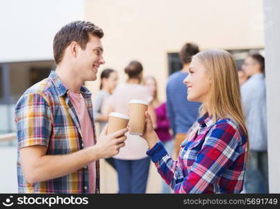 friendship, people, drinks and education concept - group of smiling students with paper coffee cups outdoors