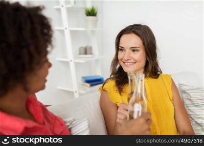 friendship, people, holidays and celebration concept - happy women clinking bottles of beer at home. happy women clinking bottles of beer at home