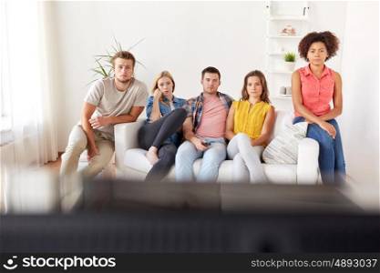 friendship, people, mass media and television concept - sad friends watching tv at home