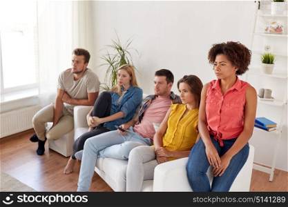 friendship, people, mass media and television concept - sad friends watching tv at home. sad friends watching tv at home