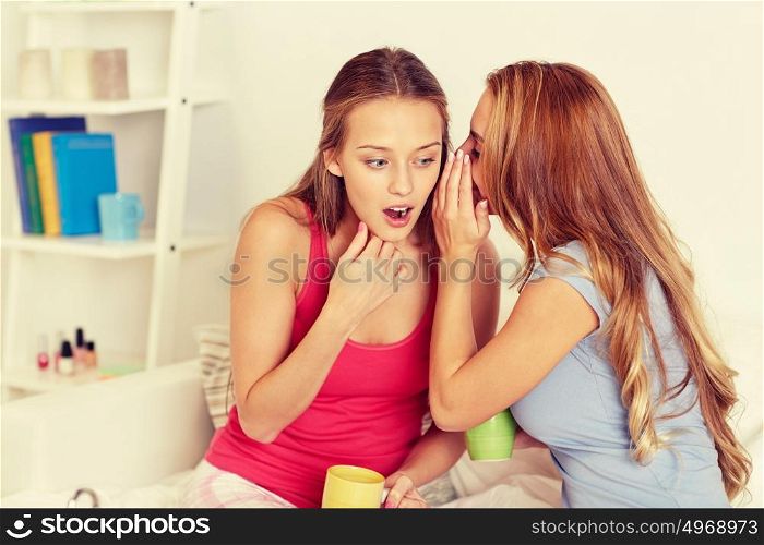 friendship, people, pajama party and communication concept - happy friends or teenage girls drinking tea with sweets and gossiping at home. young women drinking tea and gossiping at home