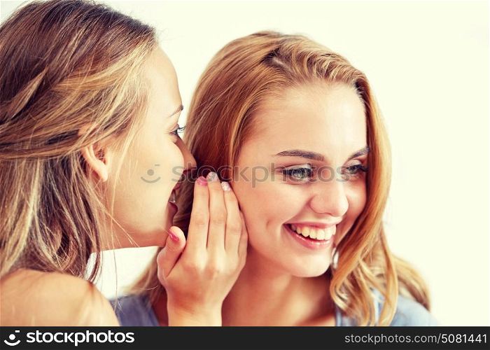 friendship, people, pajama party and communication concept - happy young women gossiping and whispering to ear at home. happy young women whispering gossip at home