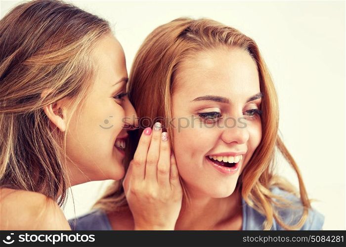 friendship, people, pajama party and communication concept - happy young women gossiping and whispering to ear at home. happy young women whispering gossip at home. happy young women whispering gossip at home