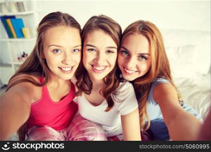 friendship, people, pajama party and fun concept - happy friends or teenage girls taking selfie at home. happy friends or teen girls taking selfie at home