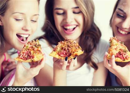 friendship, people, pajama party and junk food concept - close up of happy friends or teenage girls eating pizza at home. happy friends or teen girls eating pizza at home
