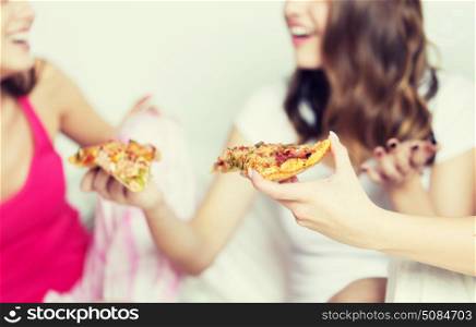 friendship, people, pajama party and junk food concept - close up of happy friends or teenage girls eating pizza at home. happy friends or teen girls eating pizza at home. happy friends or teen girls eating pizza at home