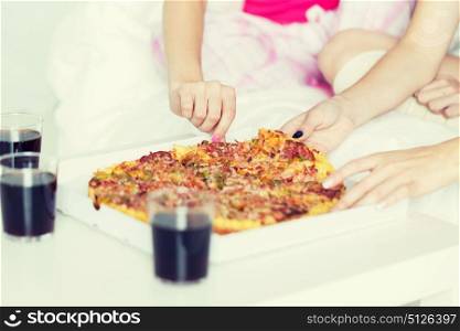 friendship, people, pajama party and junk food concept - close up of friends or teenage girls eating pizza at home. friends or teen girls eating pizza at home