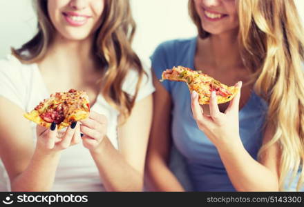 friendship, people, pajama party and junk food concept - close up of happy friends or teenage girls eating pizza at home. happy friends or teen girls eating pizza at home