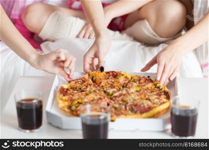 friendship, people, pajama party and junk food concept - close up of friends or teenage girls eating pizza at home