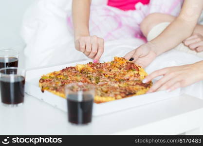 friendship, people, pajama party and junk food concept - close up of friends or teenage girls eating pizza at home