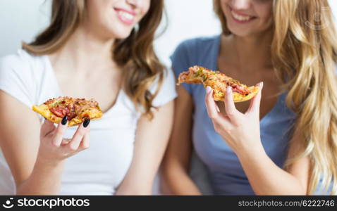 friendship, people, pajama party and junk food concept - close up of happy friends or teenage girls eating pizza at home