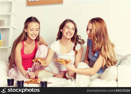 friendship, people, pajama party and junk food concept - happy friends or teenage girls eating pizza at home. happy friends or teen girls eating pizza at home