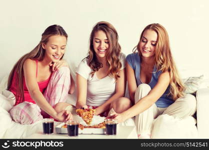 friendship, people, pajama party and junk food concept - happy friends or teenage girls eating pizza at home. happy friends or teen girls eating pizza at home