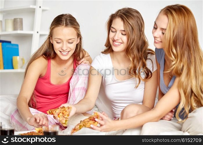 friendship, people, pajama party and junk food concept - happy friends or teenage girls eating pizza at home