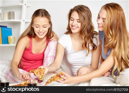 friendship, people, pajama party and junk food concept - happy friends or teenage girls eating pizza at home