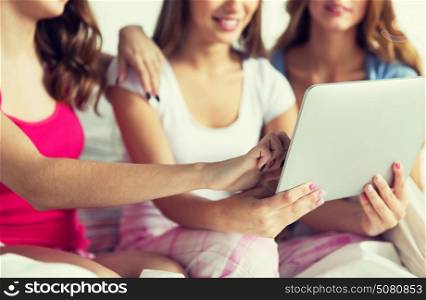 friendship, people, pajama party and technology concept - close up of happy friends or teenage girls with tablet pc computer at home. happy friends or teen girls with tablet pc at home
