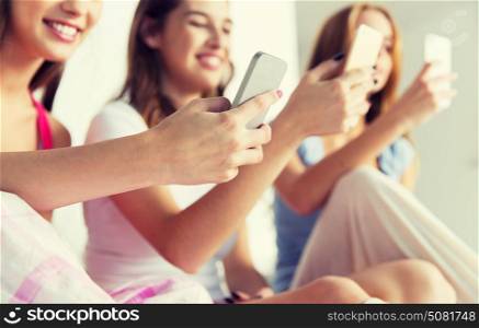 friendship, people, pajama party and technology concept - close up of happy friends or teenage girls with smartphones at home. friends or teen girls with smartphones at home