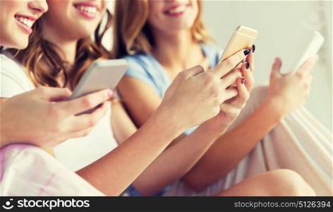 friendship, people, pajama party and technology concept - close up of happy friends or teenage girls with smartphones at home. friends or teen girls with smartphones at home