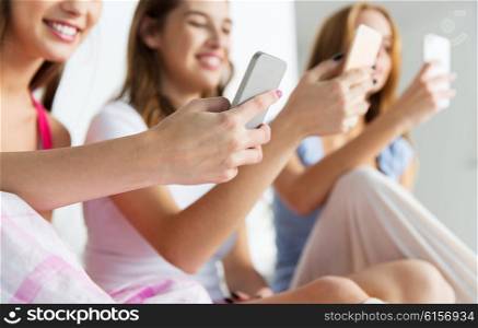 friendship, people, pajama party and technology concept - close up of happy friends or teenage girls with smartphones at home