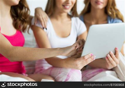 friendship, people, pajama party and technology concept - close up of happy friends or teenage girls with tablet pc computer at home