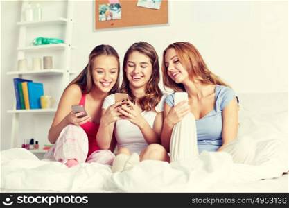 friendship, people, pajama party and technology concept - happy friends or teenage girls with smartphone at home. friends or teen girls with smartphone at home