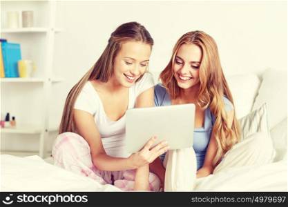 friendship, people, pajama party and technology concept - happy friends or teenage girls with tablet pc computer at home. happy friends or teen girls with tablet pc at home