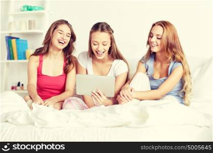 friendship, people, pajama party and technology concept - happy friends or teenage girls with tablet pc computer at home. happy friends or teen girls with tablet pc at home