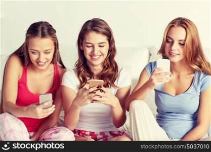 friendship, people, pajama party and technology concept - happy friends or teenage girls with smartphone at home. friends or teen girls with smartphone at home
