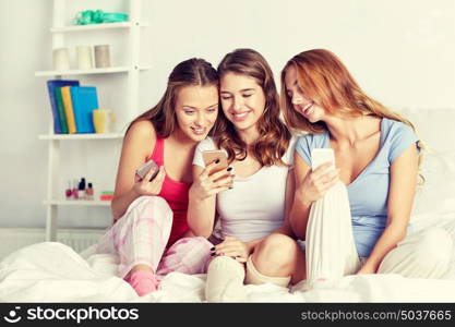 friendship, people, pajama party and technology concept - happy friends or teenage girls with smartphone at home. friends or teen girls with smartphone at home