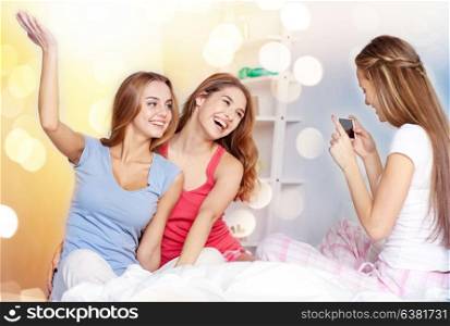 friendship, people, pajama party and technology concept - happy friends or teenage girls with smartphone taking picture at home. teen girls with smartphone taking picture at home
