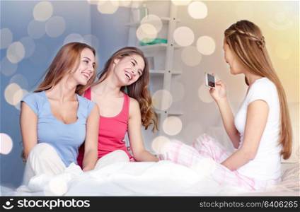 friendship, people, pajama party and technology concept - happy friends or teenage girls with smartphone taking picture at home. teen girls with smartphone taking picture at home