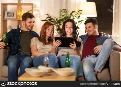 friendship, people, technology and entertainment concept - happy friends with tablet computer, snacks and non-alcoholic beer at home in evening. friends with tablet computer drinking beer at home