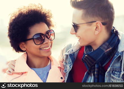 friendship, relations, tourism, travel and people concept - group of happy teenage friends or couple in sunglasses talking outdoors