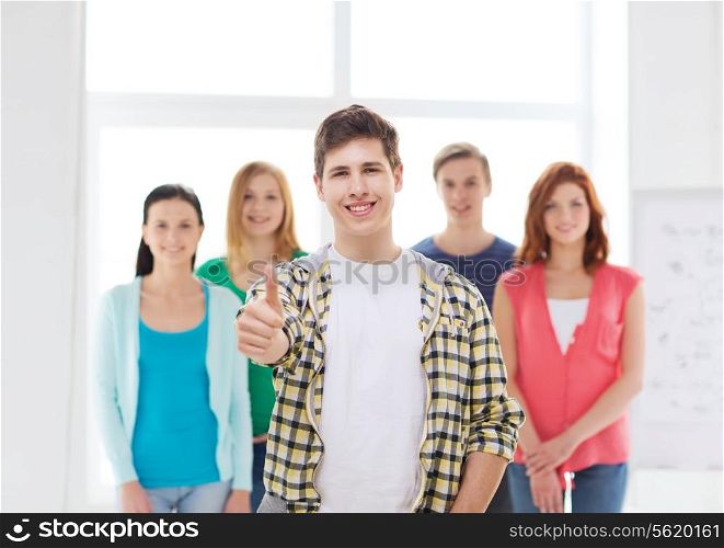 friendship, school and education concept - male student with classmates showing thumbs up gesture