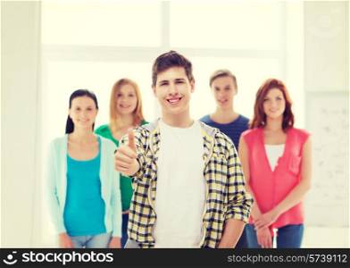 friendship, school and education concept - male student with classmates showing thumbs up gesture