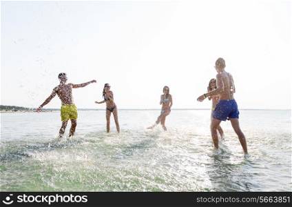 friendship, sea, summer vacation, holidays and people concept - group of happy friends having fun on summer beach