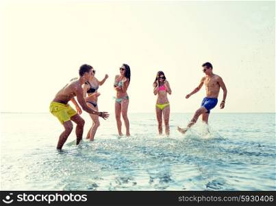 friendship, sea, summer vacation, holidays and people concept - group of happy friends having fun on beach